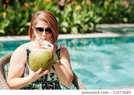 Woman enjoying coconut cocktail 72473680