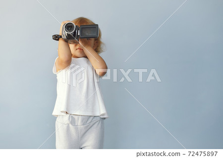 Cute little girl sitting in a studio on a blue background Cute little girl sitting in a studio on a blue background 72475897