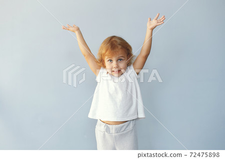 Cute little girl sitting in a studio on a blue background 72475898