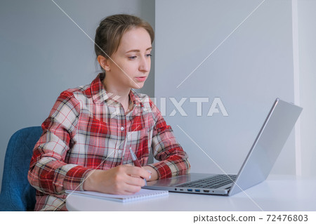 Woman using laptop, having online video call, making notes, talking at home 72476803
