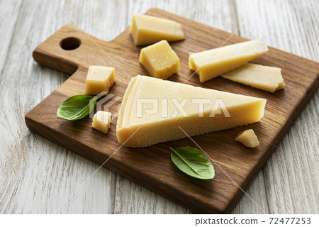 Piece of parmesan cheese on a wooden board 72477253