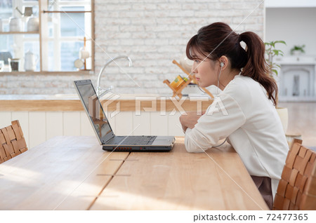 一個年輕的女人在做遠程實習在桌上使用計算機 72477365