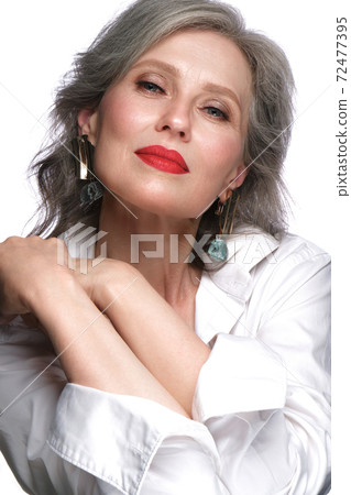 Portrait of a beautiful elderly woman in a white shirt with classic makeup and gray hair. Portrait of a beautiful elderly woman in a white shirt with classic makeup and gray hair. 72477395