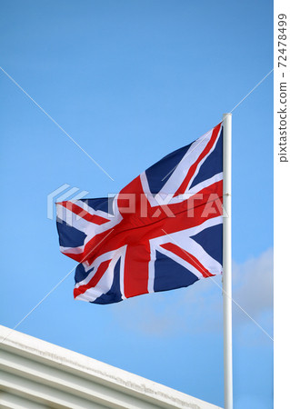 Union Jack flag on bright blue sky background. Blown away by wind.  72478499