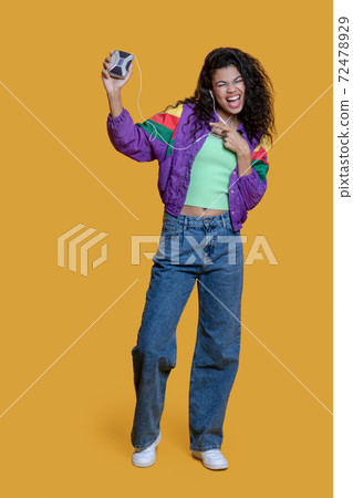 Happy dark-haired young girl with an old music player Happy dark-haired young girl with an old music player 72478929