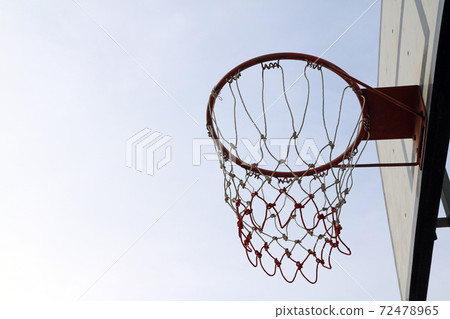 Old green board of basketball with red hoop and white-red mesh on the white sky background. 72478965