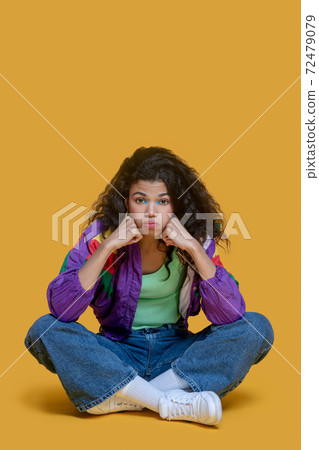 Pretty dark-haired young girl in jeans looking sad 72479079