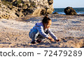 Happy little girl enjoying summer vacation and playing seashells on the beach. 72479289
