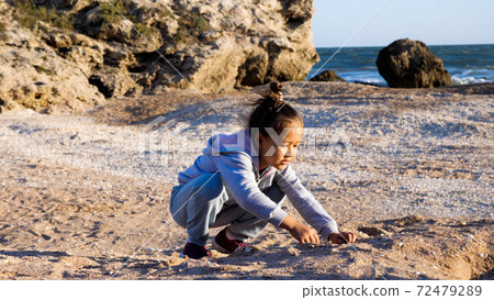Happy little girl enjoying summer vacation and playing seashells on the beach. 72479289