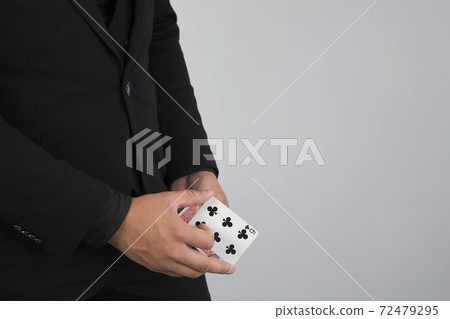 Closeup hands of magician is making trick with changing card on grey background. Closeup hands of magician is making trick with changing card on grey background. 72479295