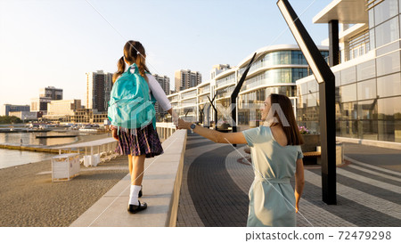 Young mother with little daughter in uniform going to school at morning Young mother with little daughter in uniform going to school at morning 72479298