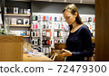 Young woman chooses a new smartphone in an electronics store. 72479300