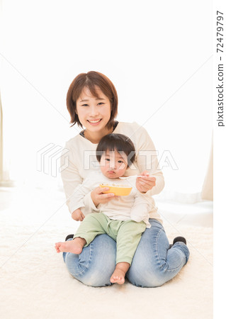 Mother giving baby food 72479797