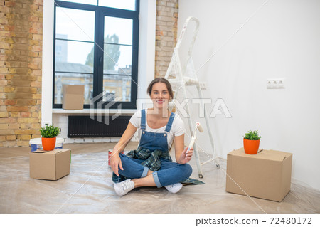 Young long-haired woman sitting on the floor and smiling 72480172