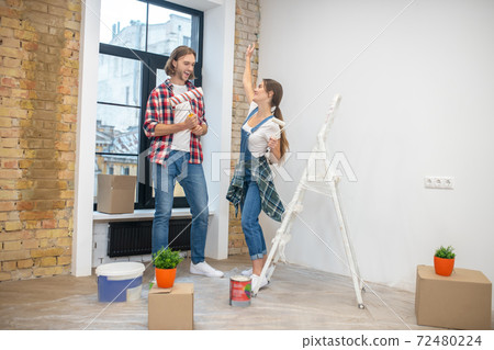Young couple standing n in the empty room ready to start paintng 72480224