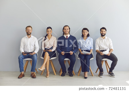 Smiling candidates job seekers sitting in row with resumes in hand and waiting for interview invitation turn 72481131
