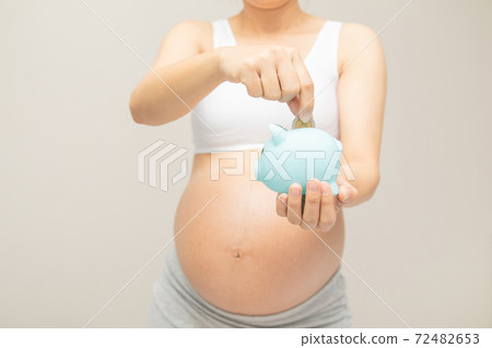 Money saving, donation, economizing, pregnancy, reservation, finance, investment and life insurance concept - young beautiful pregnant woman dropping golden coin into piggy bank glass for saving mone Money saving, donation, economizing, pregnancy, reservation, finance, investment and life insurance concept - young beautiful pregnant woman dropping golden coin into piggy bank glass for saving mone 72482653