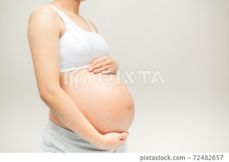 Pregnant woman touching her big belly. Close up. Motherhood, pregnancy, people and expectation concept. Pregnant woman expecting bab Pregnant woman touching her big belly. Close up. Motherhood, pregnancy, people and expectation concept. Pregnant woman expecting bab 72482657