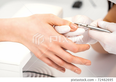 Manicure master is removing cuticles 72482695