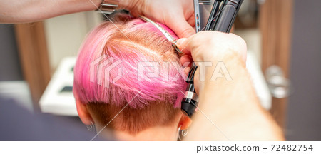 Hairdresser pinches hair with clip Hairdresser pinches hair with clip 72482754