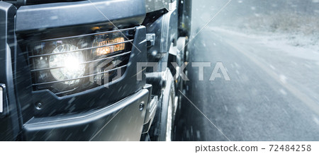The truck is driving on a winter road.  72484258
