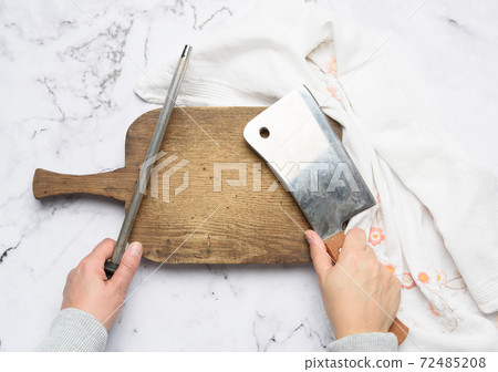 female hands hold a kitchen knife and a sharpener with a handle, the process of sharpening utensils female hands hold a kitchen knife and a sharpener with a handle, the process of sharpening utensils 72485208