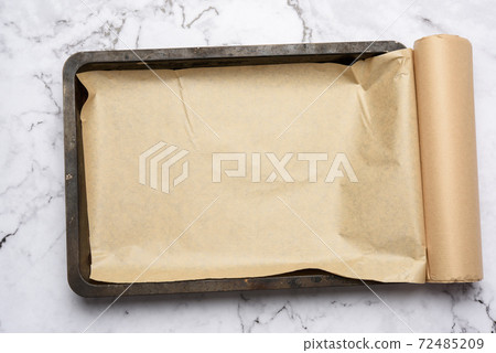 rectangular metal baking sheet and roll of brown parchment paper on white background rectangular metal baking sheet and roll of brown parchment paper on white background 72485209