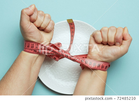 two female hands tied with red measuring tape on a white round ceramic plate, two female hands tied with red measuring tape on a white round ceramic plate, 72485210