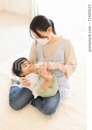Nursery teacher giving milk Nursery teacher giving milk 72485625