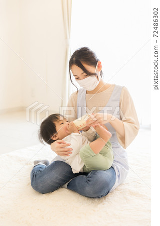 Nursery teacher giving milk Nursery teacher giving milk 72486302