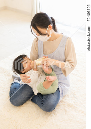 Nursery teacher giving milk Nursery teacher giving milk 72486303