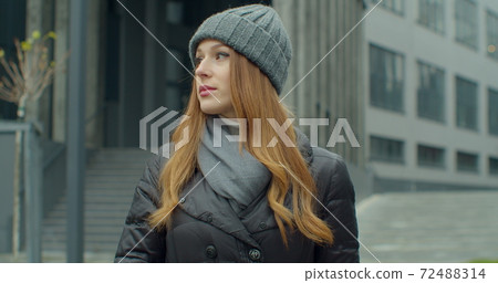 Young redhead woman portrait in a hat looking at the camera in urban background. Attractive people. Portraits. Young redhead woman portrait in a hat looking at the camera in urban background. Attractive people. Portraits. 72488314
