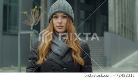 Young redhead woman portrait in a hat looking at the camera in urban background. Attractive people. Portraits. 72488315