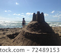 Boy looking at the sea near the sand castle 72489153