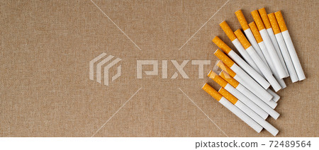 Many cigarettes are placed on the wooden floor, They are harmful to health. 72489564