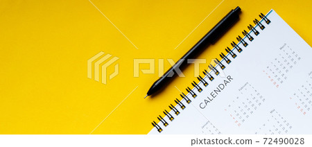 White clean calendar and pen  on  yellow background with copy space 72490028