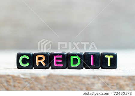 Black bead with color letter in word credit on wood background 72490178