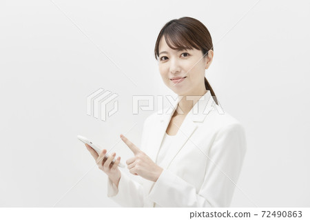 一個穿著白色西裝的女人拿著智能手機 72490863