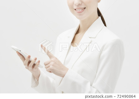 一個穿著白色西裝的女人拿著智能手機 一個穿著白色西裝的女人拿著智能手機 72490864