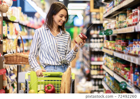 Young woman with the cart shopping in hypermarket Young woman with the cart shopping in hypermarket 72492260