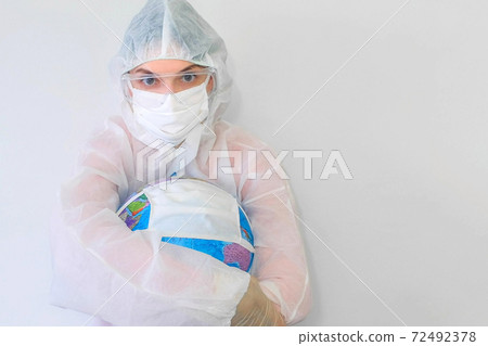 Woman doctor in protective suit, mask, glasses, gloves cuddling globe in mask. Woman doctor in protective suit, mask, glasses, gloves cuddling globe in mask. 72492378