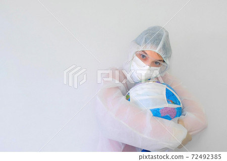Woman doctor in protective suit, mask, glasses, gloves cuddling globe in mask. Woman doctor in protective suit, mask, glasses, gloves cuddling globe in mask. 72492385