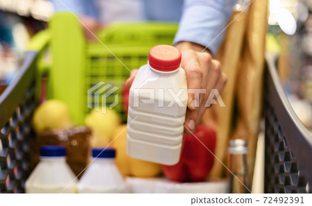 Closeup of man shopping groceries, buying milk Closeup of man shopping groceries, buying milk 72492391