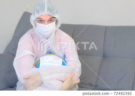 Woman doctor in protective suit, mask, glasses, gloves cuddling globe in mask. Woman doctor in protective suit, mask, glasses, gloves cuddling globe in mask. 72492392