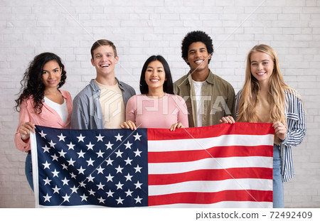 Immigration, relocation and study abroad. Cheerful young international students hold USA flag 72492409