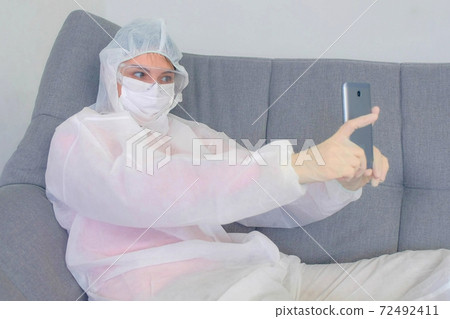 Woman in protective suit making selfie smartphone on coronavirus quarantine. Woman in protective suit making selfie smartphone on coronavirus quarantine. 72492411