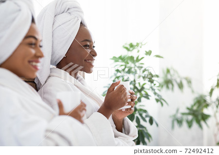 Closeup of black girlfriends in bathrobes looking at copy space Closeup of black girlfriends in bathrobes looking at copy space 72492412