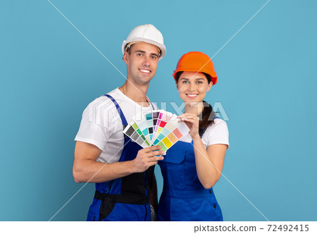Decorators man and woman in hardhats holding color swatches, ready for repair 72492415