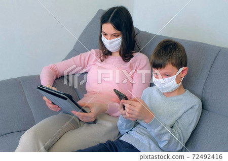 Mom and son using gadgets at home isolation on coronavirus pandemic quarantine. 72492416