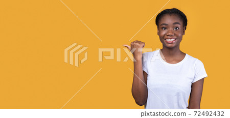 Black Woman Pointing Thumb Aside At Copy Space, Yellow Background 72492432